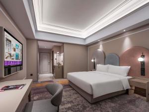 a hotel room with a bed and a tv at Mercure Beijing Downtown in Beijing