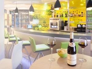 a bottle of wine sitting on a table with two glasses at ibis Styles Beaune Centre in Beaune