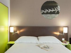 a bed with a pair of glasses on top of it at ibis Styles Beaune Centre in Beaune +52 photos