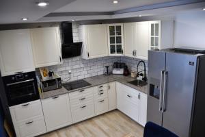 a kitchen with white cabinets and a stainless steel refrigerator at Lemon & Jacuzzi in Boguszów-Gorce