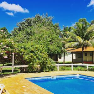 a swimming pool in front of a house with palm trees at POUSADA SERRA DA CANASTRA in Delfinópolis