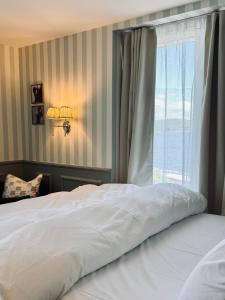 a bedroom with a white bed and a window at Vilma Sjøbad in Filtvet