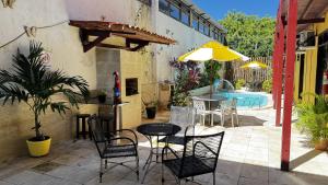 a patio with a table and chairs and a pool at Pousada Coco Verde Natal in Natal