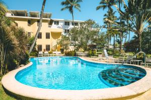 a swimming pool in front of a building with palm trees at Cabarete Palm Beach Condos in Cabarete