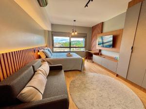 a bedroom with a couch and a bed with a window at Linked 1001 - Aconchegante e dentro do Shopping in Porto Alegre