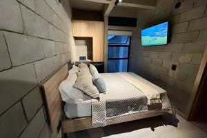 a bedroom with a bed and a tv on a brick wall at Our Home Granada in Cali
