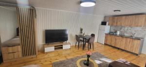 a living room with a flat screen tv and a table at Sodyba pas Babą - Apartamentai "EGLYNAS" Šventoji in Palanga