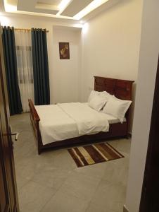a bedroom with a bed with white sheets and pillows at Résidence Prestige KGV Appt 304 in Douala