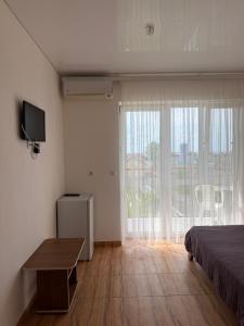 a bedroom with a bed and a television and a window at Sakura Hotel in Zatoka