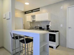 a kitchen with white cabinets and a counter with stools at Life Center in Caruaru