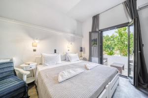 a white bedroom with a bed and a window at Guesthouse Perdikouli in Aliki