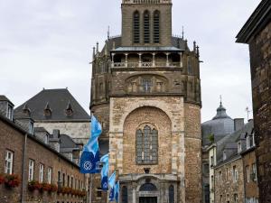 a tall building with a clock tower with flags at ibis budget Aachen City in Aachen