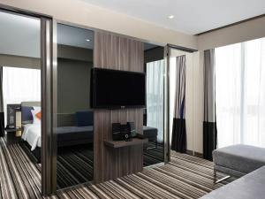 a hotel room with a flat screen tv and a bedroom at Novotel Bangkok IMPACT in Nonthaburi +180 photos