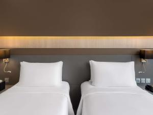 two beds sitting next to each other in a room at Mercure Bangkok Siam in Bangkok