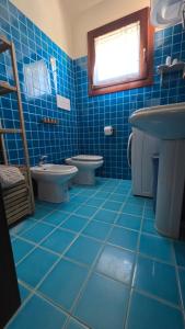 a blue tiled bathroom with two toilets and a sink at Villa Angedras in San Teodoro +21 photos