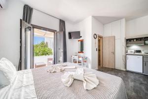a bedroom with a large white bed with a large window at Guesthouse Perdikouli in Aliki