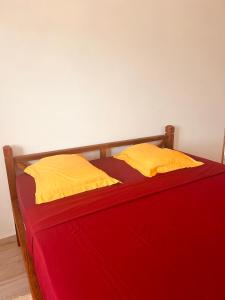 a red bed with two yellow pillows on it at Cap Alizés in Petit-Canal