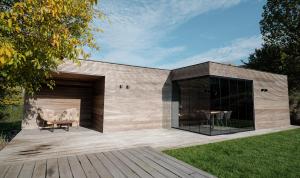 a building with a wooden deck with a table and chairs at Maison Lillie in Zonnebeke