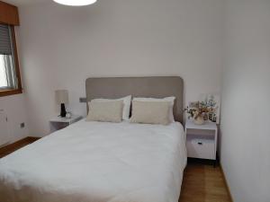 a bedroom with a large white bed with two pillows at Brisas de Malpica in Malpica