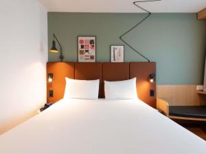 a bedroom with a large bed with two white pillows at ibis Genève Centre Nations in Geneva +68 photos