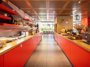 a large kitchen with red cabinets and a long corridor at ibis Genève Centre Nations in Geneva