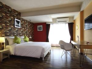 a bedroom with a white bed and a brick wall at ibis Styles Chiang Mai in Chiang Mai