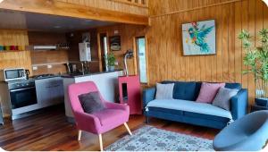 a living room with a blue couch and pink chairs at CostaLoft in Valdivia