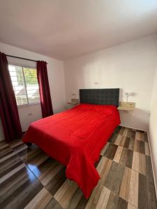 a bedroom with a red bed and a window at Colibrí in Merlo