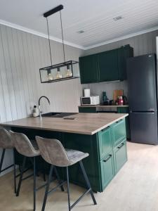 a kitchen with green cabinets and a kitchen island with chairs at Apšuciema Birzīši in Apšuciems