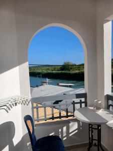 a patio with a table and a boat on the water at Acheron rooms in Preveza