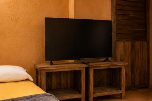a flat screen tv on a wooden stand in a room at Ixak Cabañas in La Pimienta