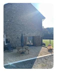 a stone building with a bench and an umbrella at L Appart in Saint-Éloi