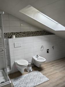 a white bathroom with a toilet and a sink at Work & Stay Peine, Parkplatz, WLAN, Küche inkl in Peine +2 photos