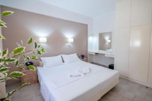 a bedroom with a white bed with two glasses on it at Corfu Glyfada Beach Apartments in Glyfada +22 photos