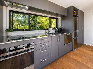 a kitchen with gray cabinets and a large window at Art Lovers Retreat - Stay Waiheke in Onetangi