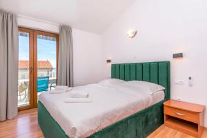 a bedroom with a large bed with a green headboard at Apartments Adriatic Relax, heated pool, parking place in Duće +80 photos
