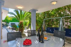 a table with wine glasses and a bowl of fruit at Apartments Adriatic Relax, heated pool, parking place in Duće