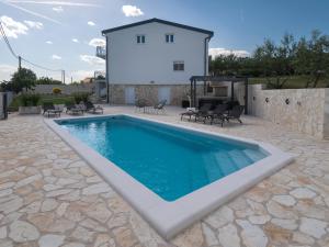a swimming pool in a patio with a house at Villa The Rock in Unešić