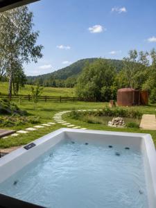 a bath tub filled with water in a field at Krzywe Pearl Chalets in Krywe