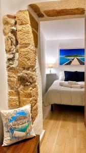 a bedroom with a bed and a stone wall at Carbonari Holiday House in Cefalù