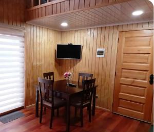 a dining room with a table and chairs and a television at CostaLoft in Valdivia