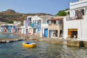 a yellow boat in the water next to houses at Rota in Klima