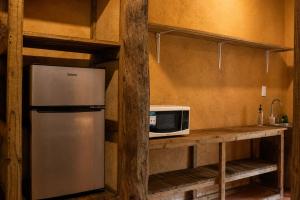 a kitchen with a refrigerator and a microwave on a shelf at Ixak Cabañas in La Pimienta