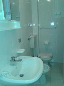 La salle de bains blanche est pourvue d'un lavabo et de toilettes. dans l'établissement Albergo Ristorante Poli, à Madonna di Fornelli