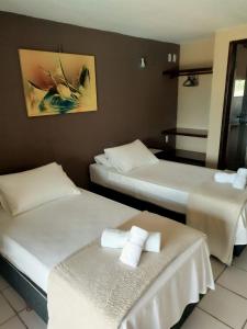 two beds in a hotel room with towels on them at Pousada Tartaruga Cumbuco in Cumbuco
