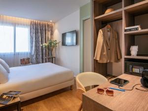 a hotel room with a bed and a suit on a shelf at ibis Styles Beaulieu sur Mer in Beaulieu-sur-Mer