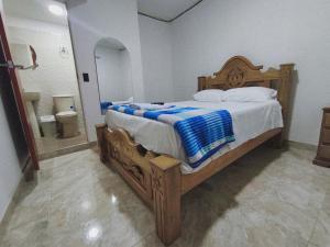 a bedroom with a wooden bed and a bathroom at Hotel El Empedrado in Popayan