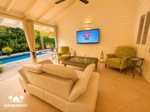 a living room with a couch and a tv at Villa 300m from beach with shared swimming pool in Las Terrenas