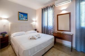 a bedroom with a large white bed and a mirror at Corfu Glyfada Beach Apartment in Glyfada