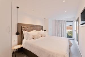 a white bedroom with a large bed and a window at VILLA STONE PEARL SUTIVAN - exceptional luxury new three-room villa - private pool and jacuzzi - perfect location right next to the town center and the beach - secured parking space in Sutivan +39 photos